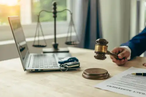 attorney hitting gavel on desk with laptop, toy car, and scale
