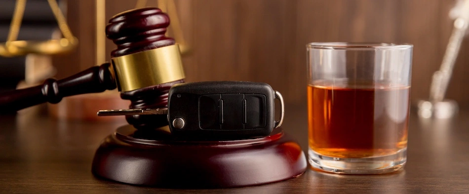 A gavel and glass of scotch represent what happens after being in a car accident due to getting a DUI.