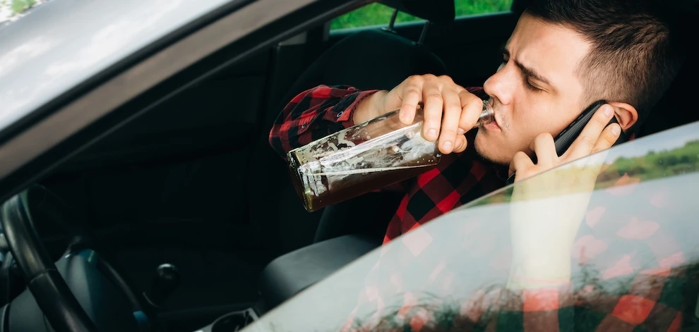 A young male is about to get in a car accident after drinking and driving.